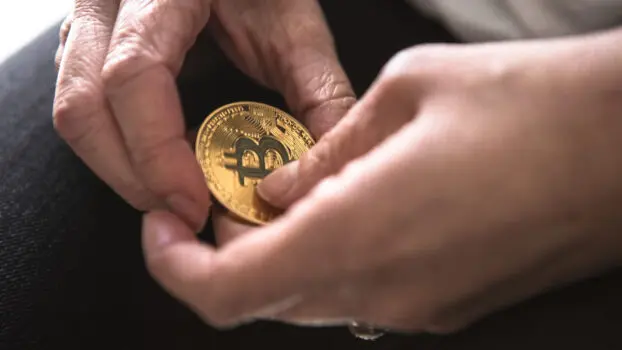 person holding a physical bitcoin and wondring what is the best way to store crypto